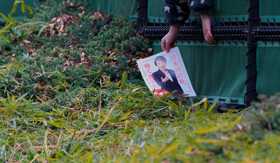 A supporter picks up a leaflet featuring Japan's prime minister during a campaign event on 7 February 2026. Credit: Associated Press
