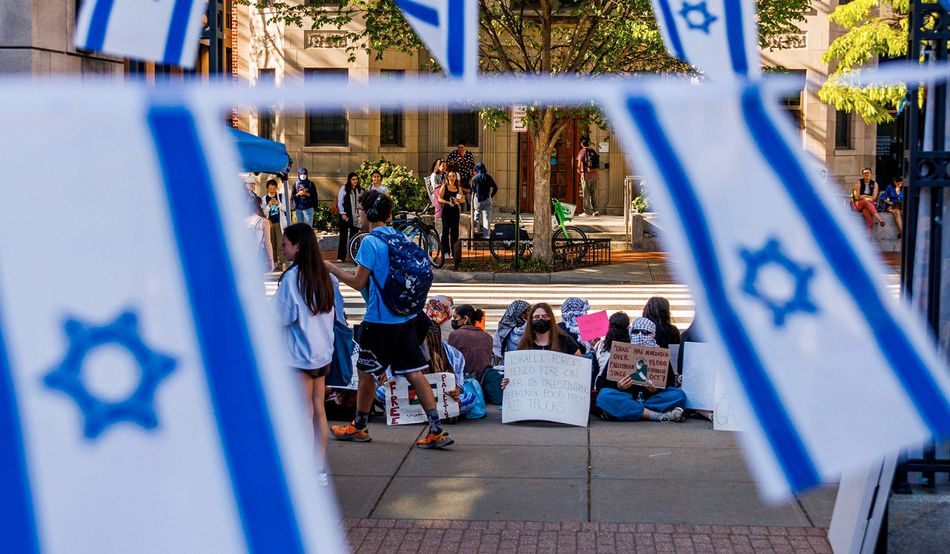 In Kogan Plaza in George Washington University in Washington, District of Columbia, students sit in support of Palestinians. Bunting of the flag of Israel is in the foreground.