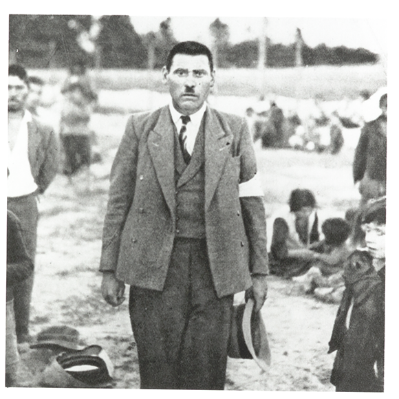 Photograph of a Roma man, thought to be Jozef Kwiek, Belzec, German-occupied Poland, 1940. Romani families in the background. Photo: Wiener Holocaust Library Collections