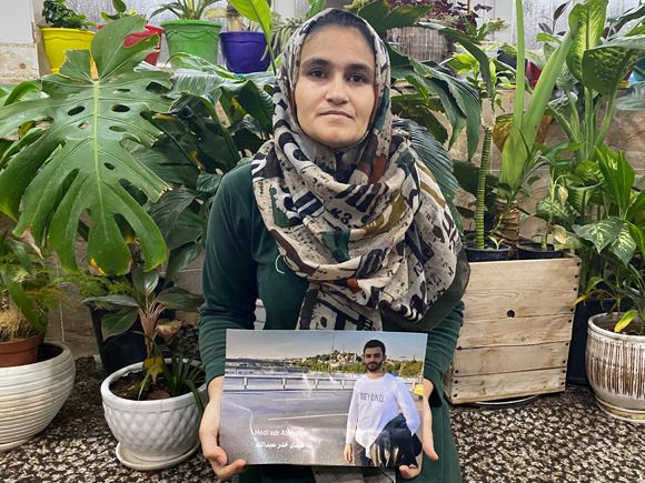 Saresh Khdir holds a photo of her brother Hedi, who has been missing since a boat he was travelling in to Europe sunk off Crete in 2021