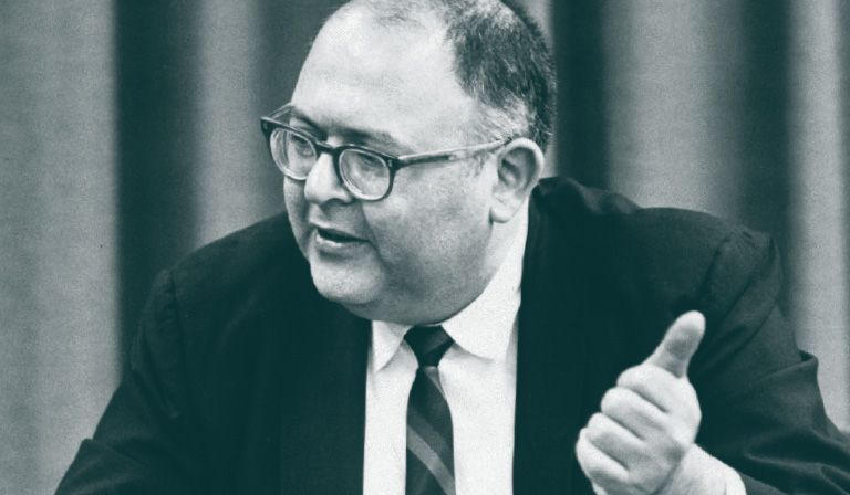 A black and white photograph of Herman Kahn, wearing a black suit, white shirt, tie and glasses
