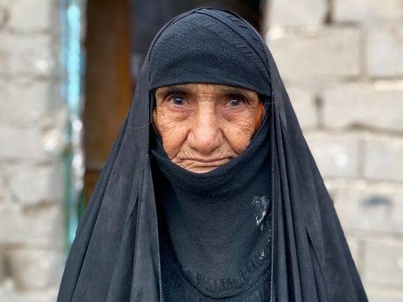 Enhaira Raheyef Shannan stands outside the rough breeze-block hut that is her home in Al Hilal, Muthanna province
