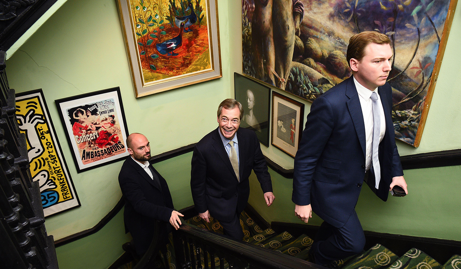 Nigel Farage walks behind George Cottrell to the unveiling of a portrait of Farage titled Mr Brexit, 2020. Image by Alamy / PA Images / Kirsty O'Connor