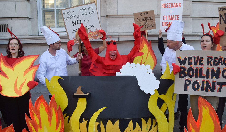 An activist dressed as a lobster is 'cooked alive' by peers dressed as ‘Shell chefs’ during a protest outside a government building