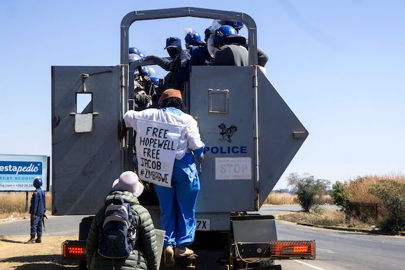 Zimbabwean novelist Tsitsi Dangarembga (C) and a colleague Julie Barnes hold placards as they are arrested during an anti-corruption protest march along Borrowdale road, on July 31, 2020 in Harare. - Police in Zimbabwe arrested on July 31, 2020 internatio