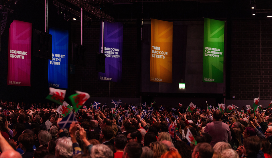 People wave Welsh and Scottish flags as Keir Starmer delivers his leaders speech at Labour's party conference. Image: Milo Chandler/Alamy.