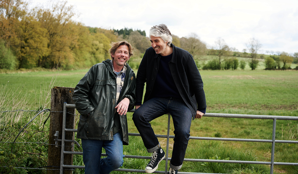 Andy Cato leans on a farm gate, which co-founder George Lamb is sitting on. Image: Waitrose
