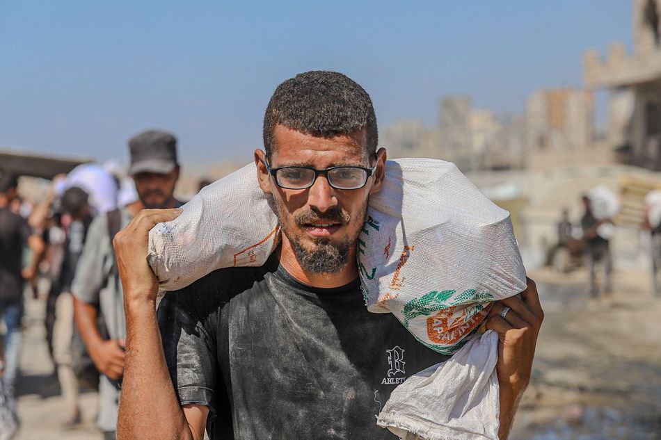 Palestinians gather at an aid distribution centre near the Zikim border crossing in Gaza to access limited food on 5th August, 2025. Image: Abaca Press/Alamy