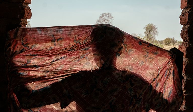 Susu rearranges her headscarf © Guy Peterson