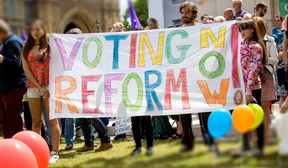 Two girls hold a colourful banner that reads "Voting reform now!" Image: © Paul Davey/Alamy